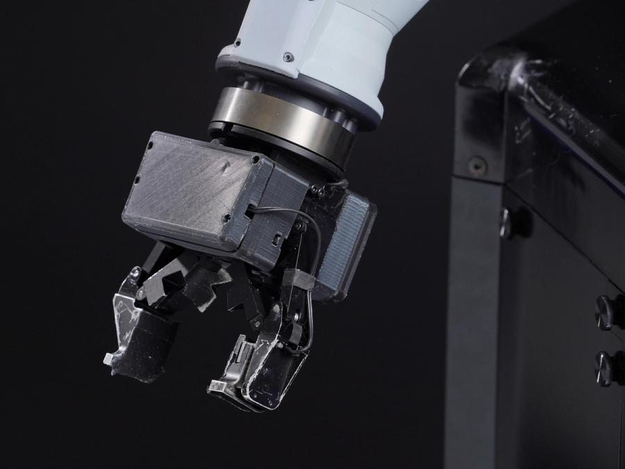 Close-up of a robot hand consisting of a metal two-fingered gripper.