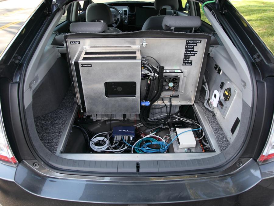 The cars open trunk shows silver boxes, routers and other equipment.
