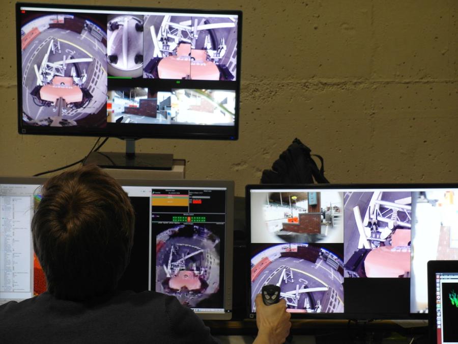 Back view of a person looking at multiple computer monitors showing views from the robot.