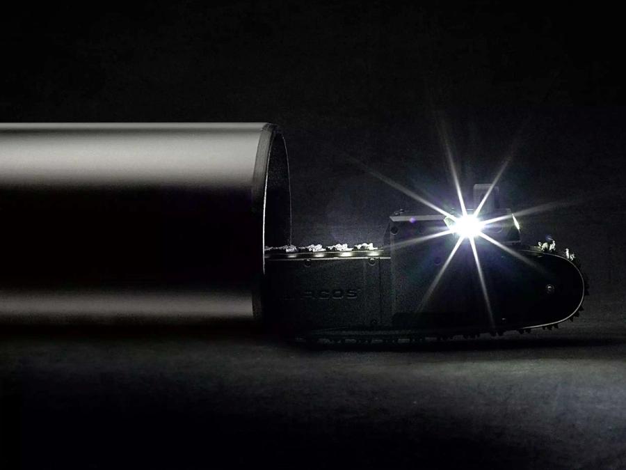 A bright light shines from the robot, which is partially inside a dark pipe.