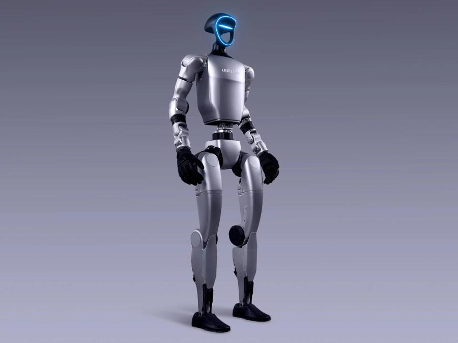 Unitree Robotics' G1 bipedal humanoid robot has two arms ending in black gloved 5 digit hands. It's blue-lit frame shaped face has cameras and sensors.