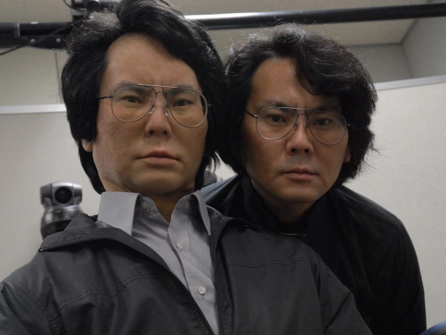 The robot and its inventor pose with their faces next to each other to show how alike they look.