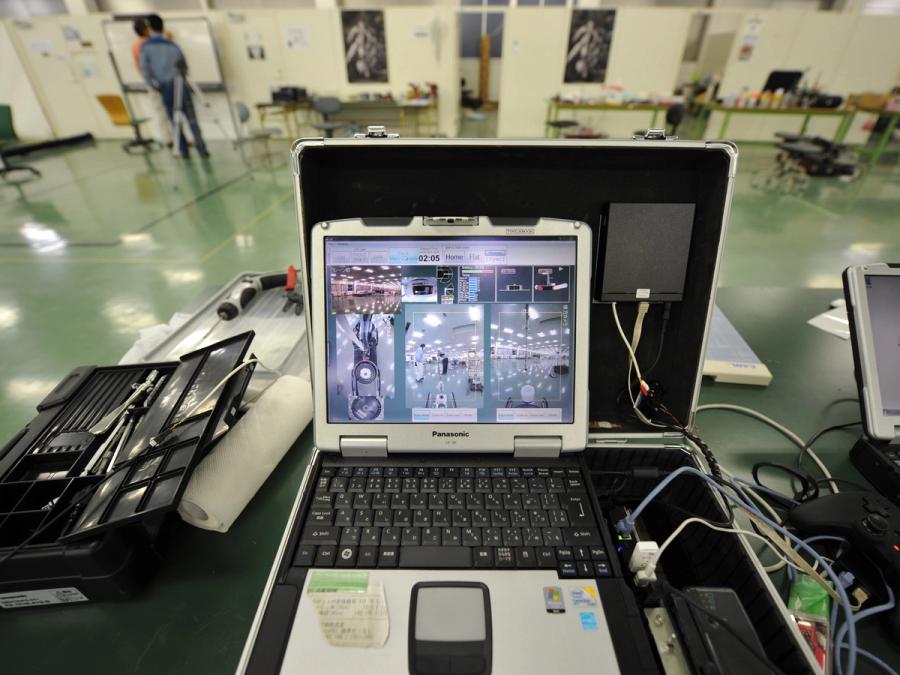 An open suitcase houses a laptop computer and electronics. The computer screen shows the robots camera views.